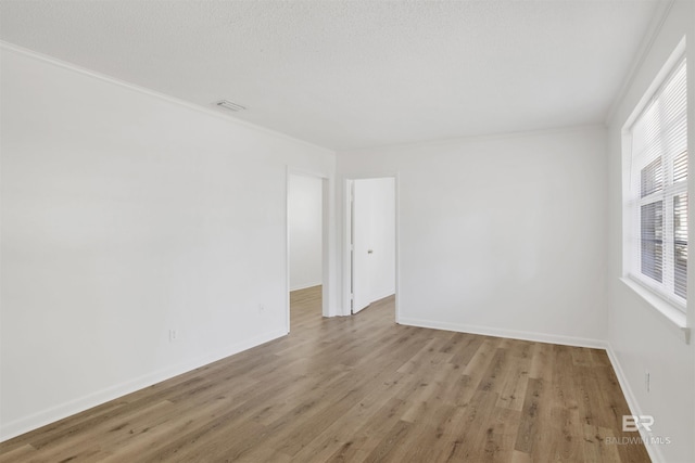 unfurnished room featuring visible vents, baseboards, wood finished floors, and crown molding