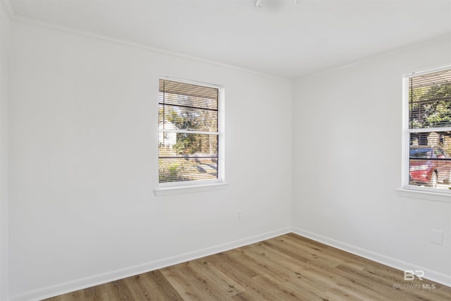 unfurnished room featuring light wood-type flooring, baseboards, and crown molding