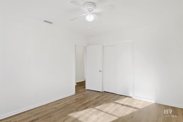 unfurnished bedroom featuring visible vents, wood finished floors, a closet, baseboards, and ceiling fan