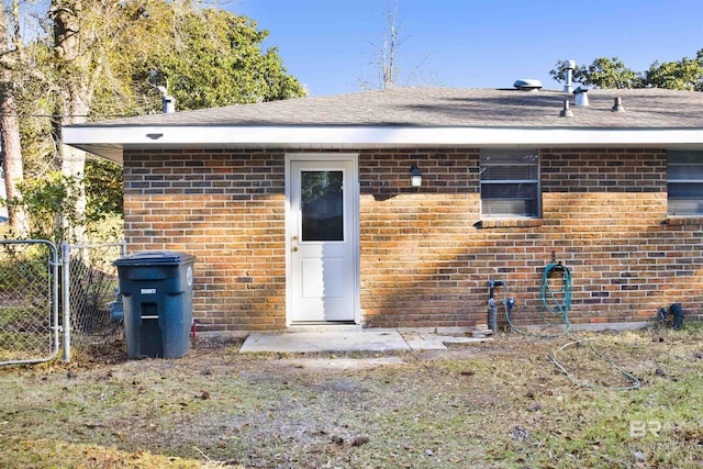 back of property featuring brick siding, a gate, and fence