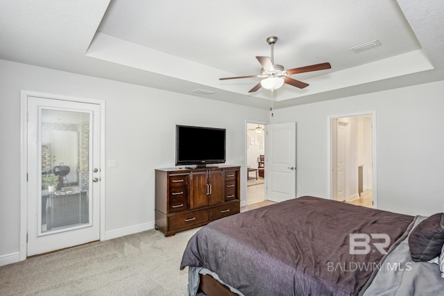 carpeted bedroom with a raised ceiling and ceiling fan