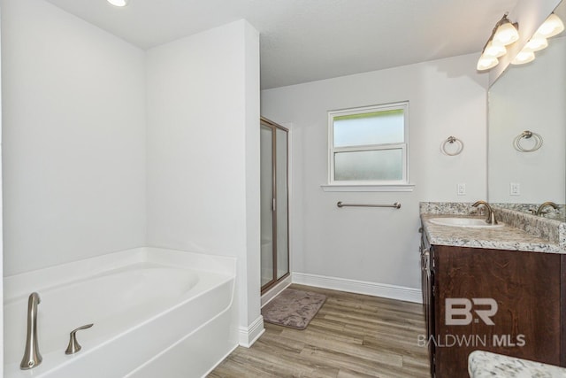 bathroom with hardwood / wood-style floors, independent shower and bath, and vanity