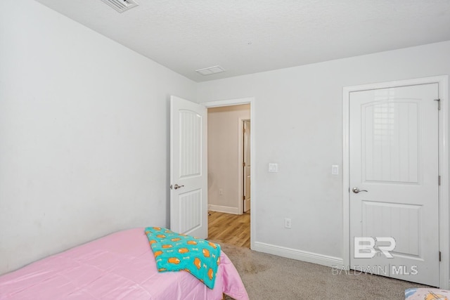 bedroom featuring a textured ceiling and light carpet