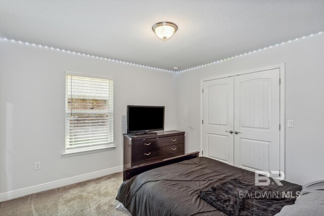 bedroom with a closet, multiple windows, carpet flooring, and a textured ceiling