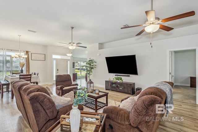 living room featuring ceiling fan with notable chandelier and light wood-type flooring