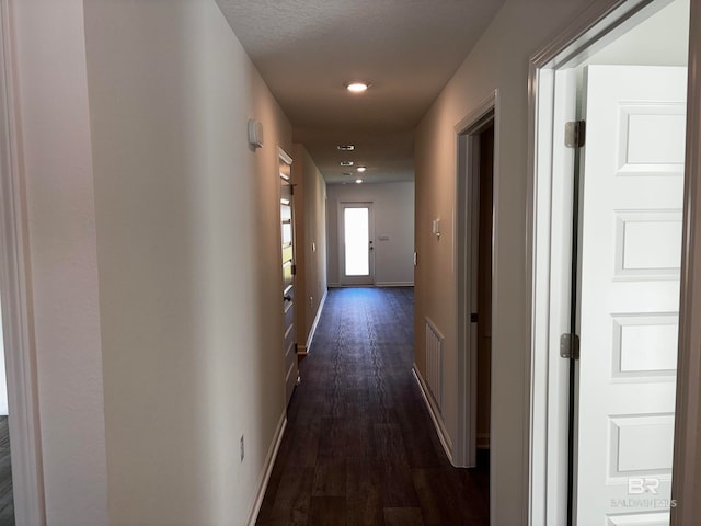 corridor with dark hardwood / wood-style floors and a textured ceiling