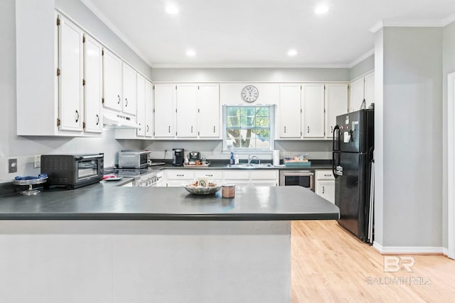 kitchen featuring white cabinets, ornamental molding, black refrigerator, and kitchen peninsula