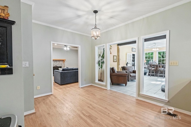 interior space with ornamental molding, an inviting chandelier, and light hardwood / wood-style flooring