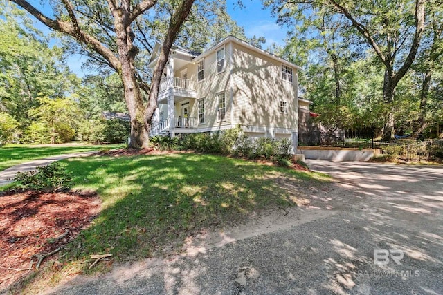 view of side of property featuring a balcony and a yard