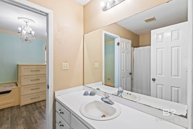 bathroom featuring hardwood / wood-style floors, crown molding, vanity, and an inviting chandelier