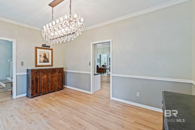 unfurnished dining area featuring light wood-type flooring, crown molding, and an inviting chandelier