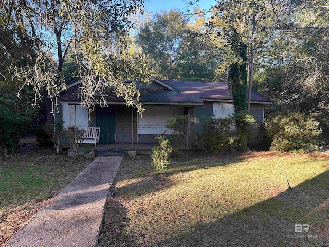 ranch-style house featuring covered porch and a front lawn