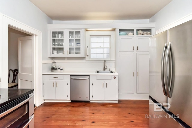 kitchen featuring white cabinetry, appliances with stainless steel finishes, sink, and dark wood-type flooring