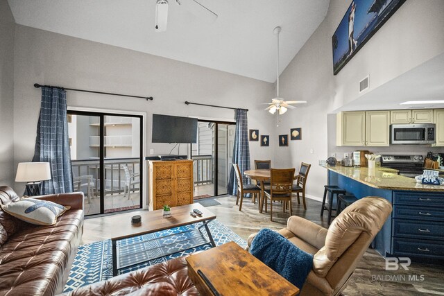 living room with high vaulted ceiling, wood finished floors, visible vents, a ceiling fan, and baseboards