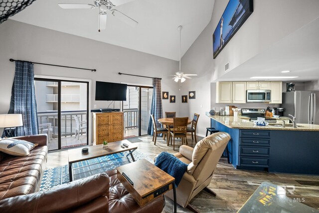 living room featuring ceiling fan, high vaulted ceiling, and wood finished floors