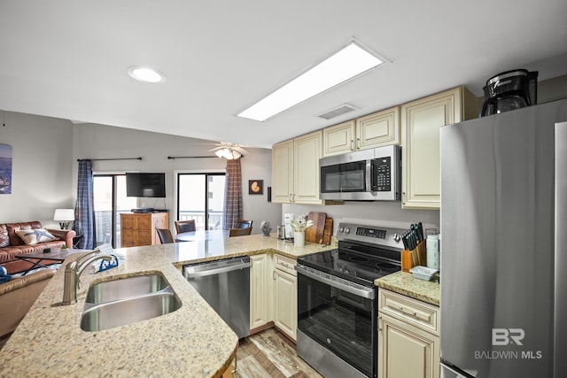 kitchen featuring visible vents, appliances with stainless steel finishes, open floor plan, cream cabinets, and a sink