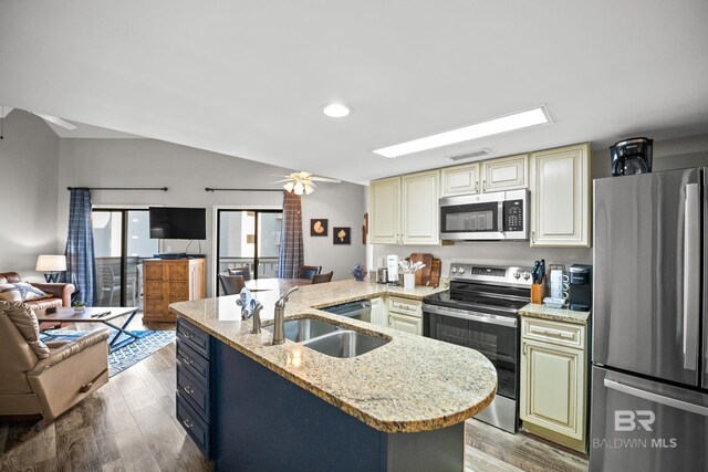 kitchen with cream cabinetry, visible vents, appliances with stainless steel finishes, open floor plan, and a sink