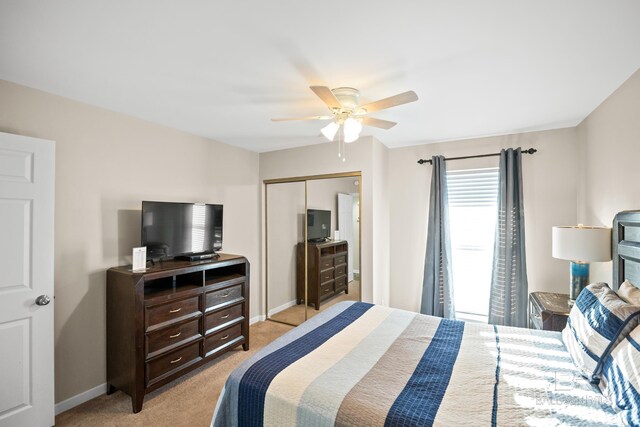 bedroom with a closet, light carpet, ceiling fan, and baseboards