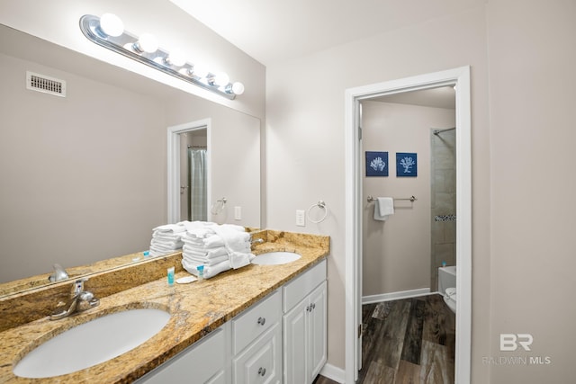 bathroom with wood finished floors, visible vents, a sink, and double vanity