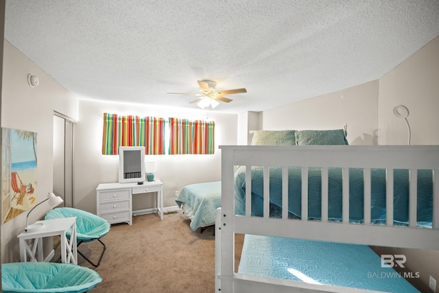 bedroom with ceiling fan, a textured ceiling, carpet, and a closet