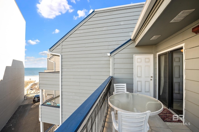 balcony featuring a water view, a view of the beach, and outdoor dining space