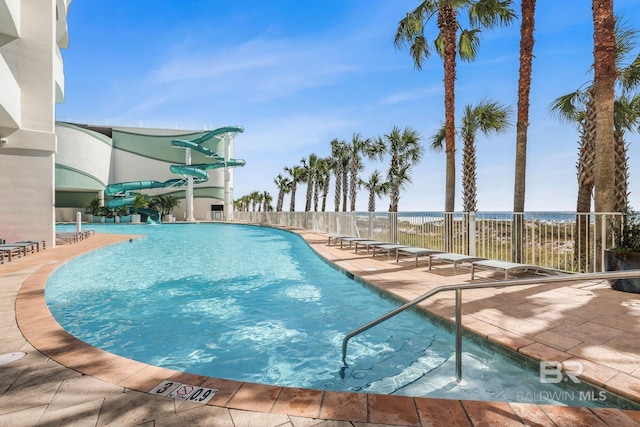 view of pool with a water view, a water slide, and a patio