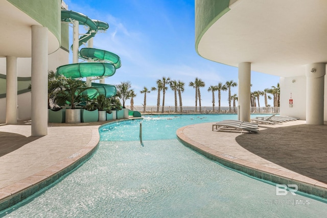 view of pool with a patio area, a water view, and a water slide