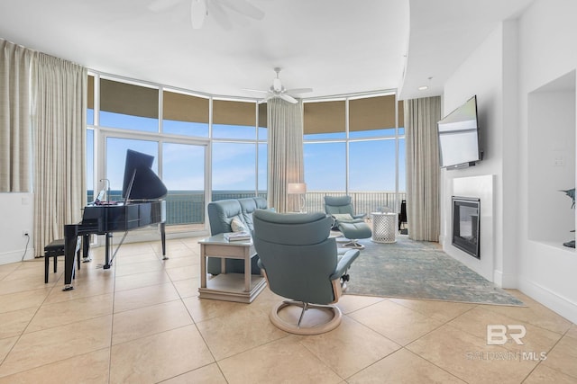 living room with ceiling fan, expansive windows, and light tile patterned flooring