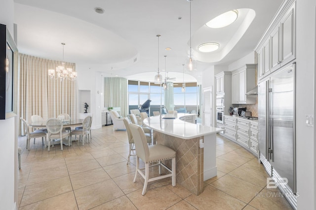 kitchen with light tile patterned floors, appliances with stainless steel finishes, a breakfast bar area, and decorative light fixtures