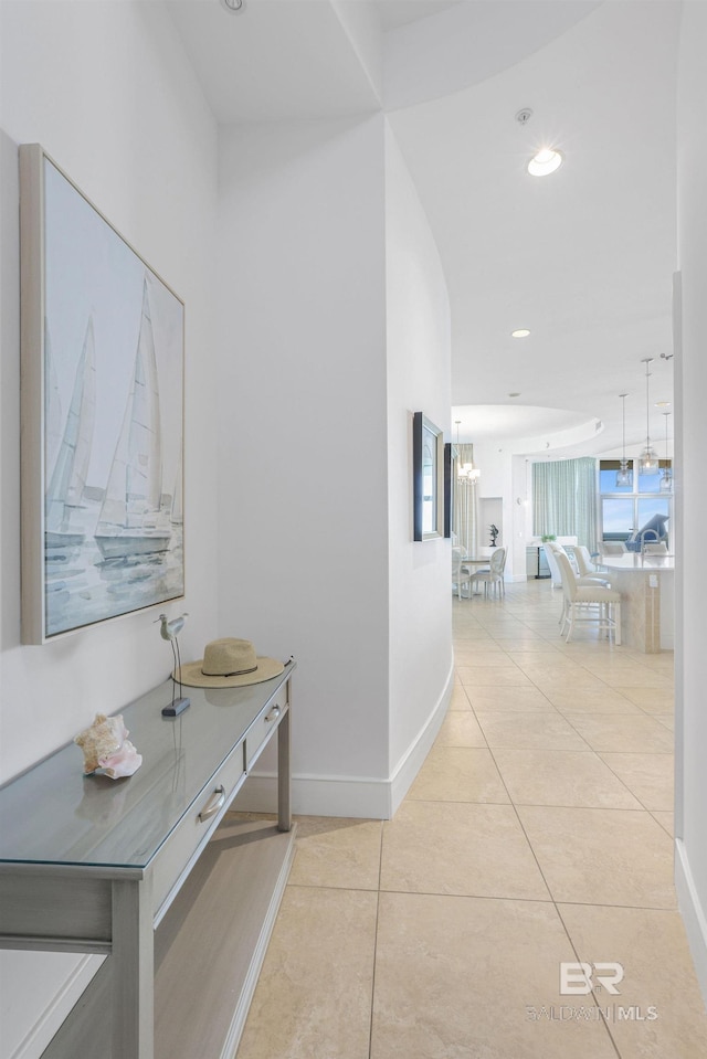 hallway with an inviting chandelier and light tile patterned flooring