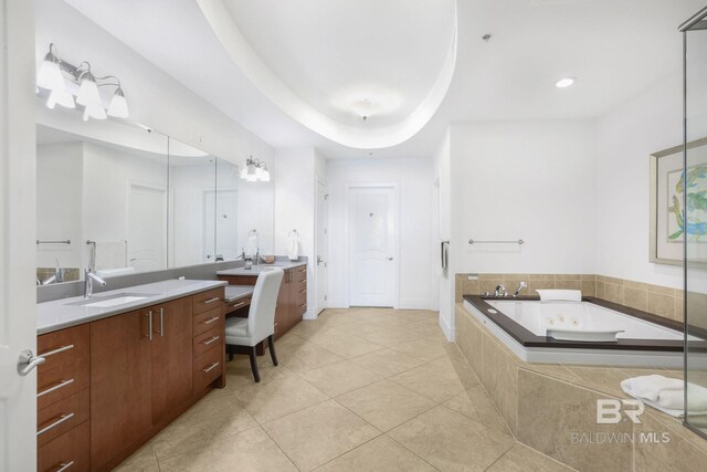 bathroom with vanity, a relaxing tiled tub, a tray ceiling, and tile patterned flooring