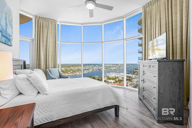 bedroom featuring expansive windows, light hardwood / wood-style flooring, multiple windows, and ceiling fan