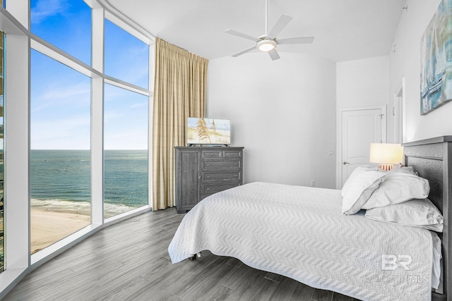 bedroom with access to outside, a beach view, hardwood / wood-style floors, ceiling fan, and a water view