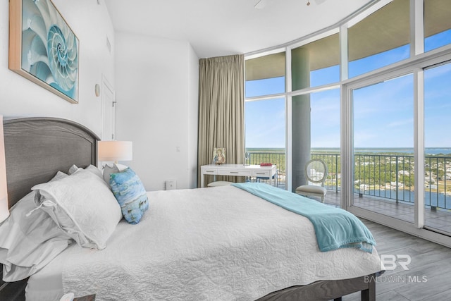 bedroom featuring hardwood / wood-style floors, access to exterior, and expansive windows