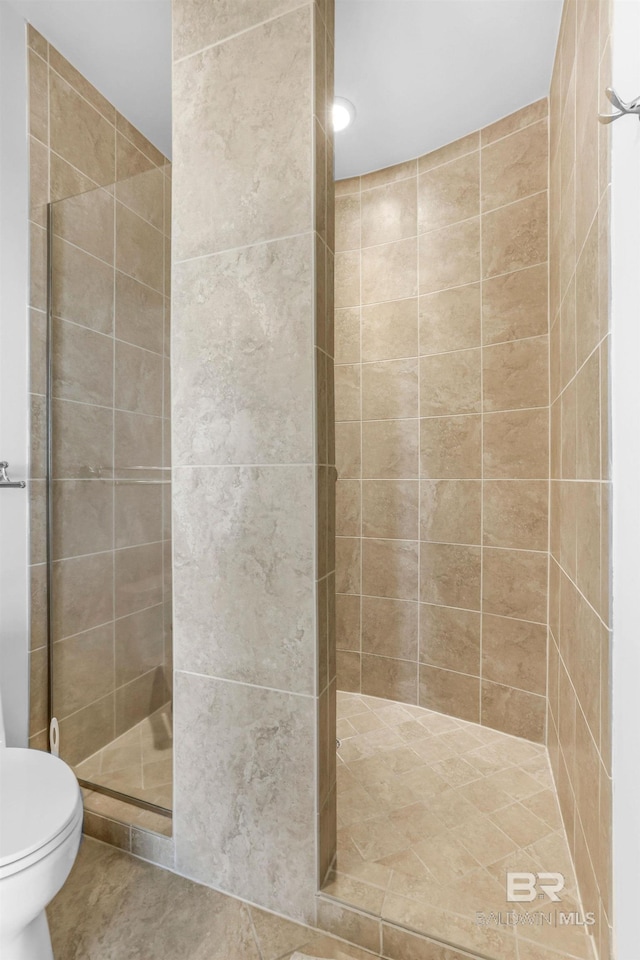 bathroom featuring tiled shower, toilet, and tile patterned floors