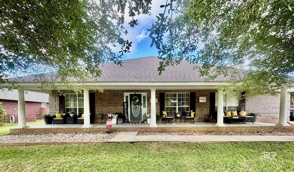 back of house featuring an outdoor hangout area, a yard, a porch, and brick siding