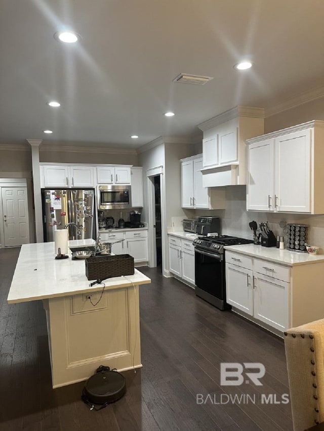 3872 Stafford Blvd, Gulf Shores, AL 36542 - kitchen featuring appliances with stainless steel finishes, crown molding, white cabinetry, decorative backsplash, and dark wood-style flooring