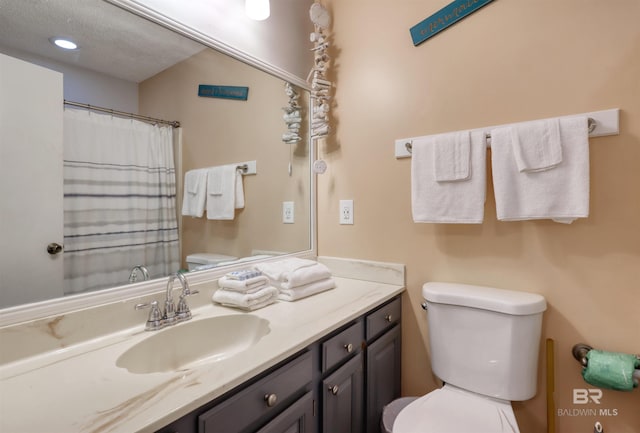 bathroom featuring a textured ceiling, vanity, and toilet