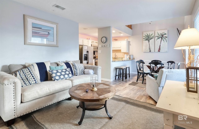 living room featuring sink and light hardwood / wood-style flooring