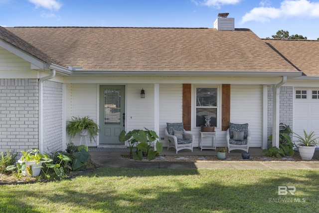 view of exterior entry with a lawn, a porch, and a garage