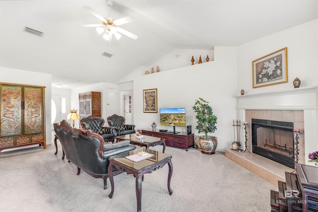 living room featuring vaulted ceiling, a tiled fireplace, carpet floors, and ceiling fan