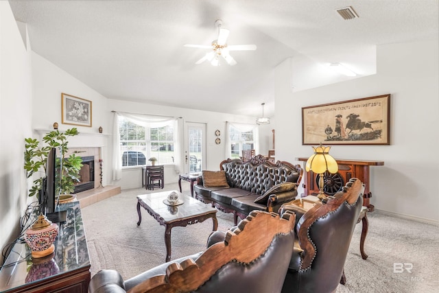 carpeted living room featuring lofted ceiling, a textured ceiling, a fireplace, and ceiling fan