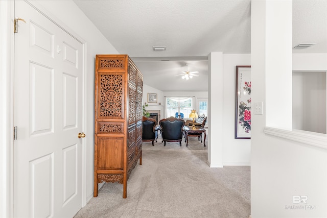 hall featuring a textured ceiling and light colored carpet