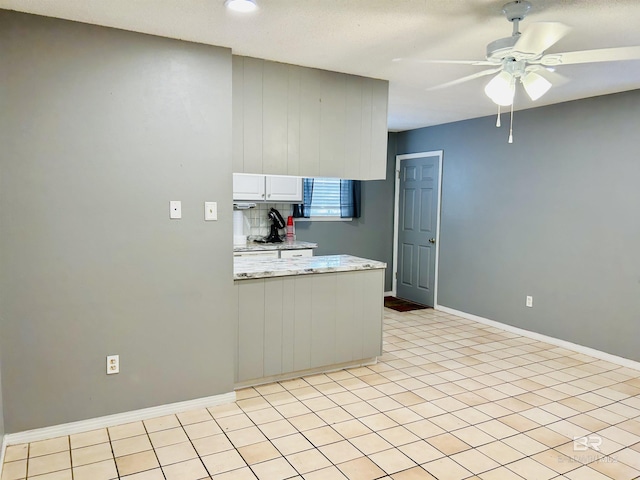 kitchen with white cabinetry, ceiling fan, light stone countertops, and light tile patterned floors