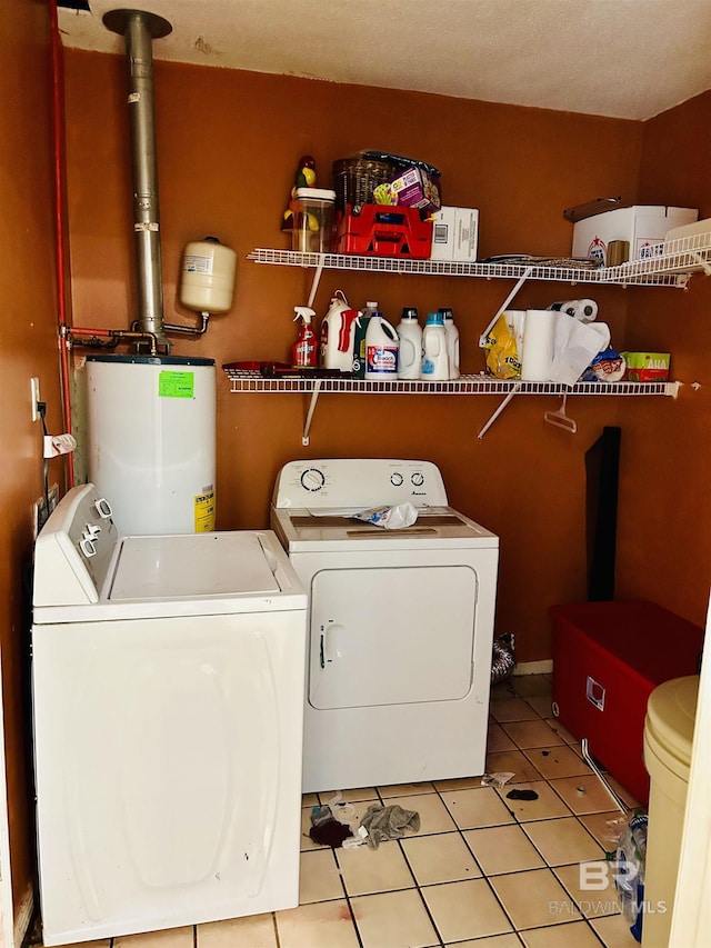 clothes washing area featuring light tile patterned flooring, washing machine and clothes dryer, and water heater