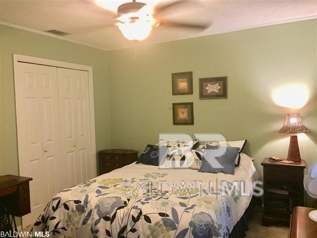 bedroom with ornamental molding, carpet floors, ceiling fan, and a closet