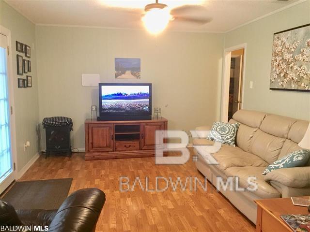 living room featuring crown molding, wood-type flooring, and ceiling fan