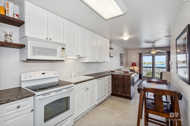 kitchen featuring dark countertops, open shelves, a sink, and white appliances