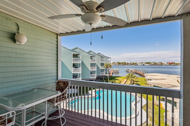 wooden deck featuring a community pool, a water view, and ceiling fan