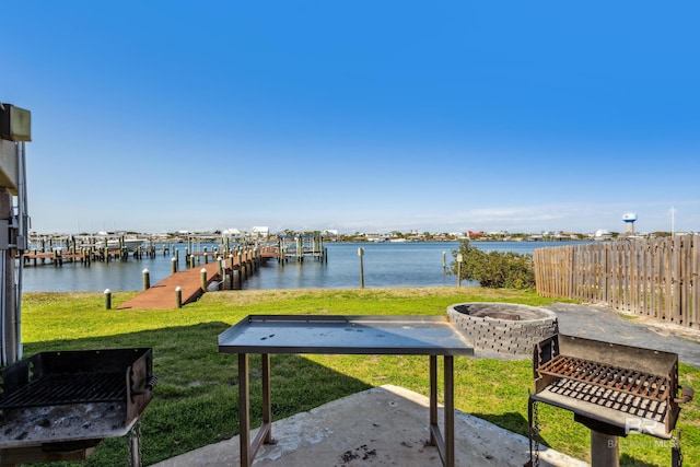 view of yard featuring fence, a boat dock, an outdoor fire pit, and a water view